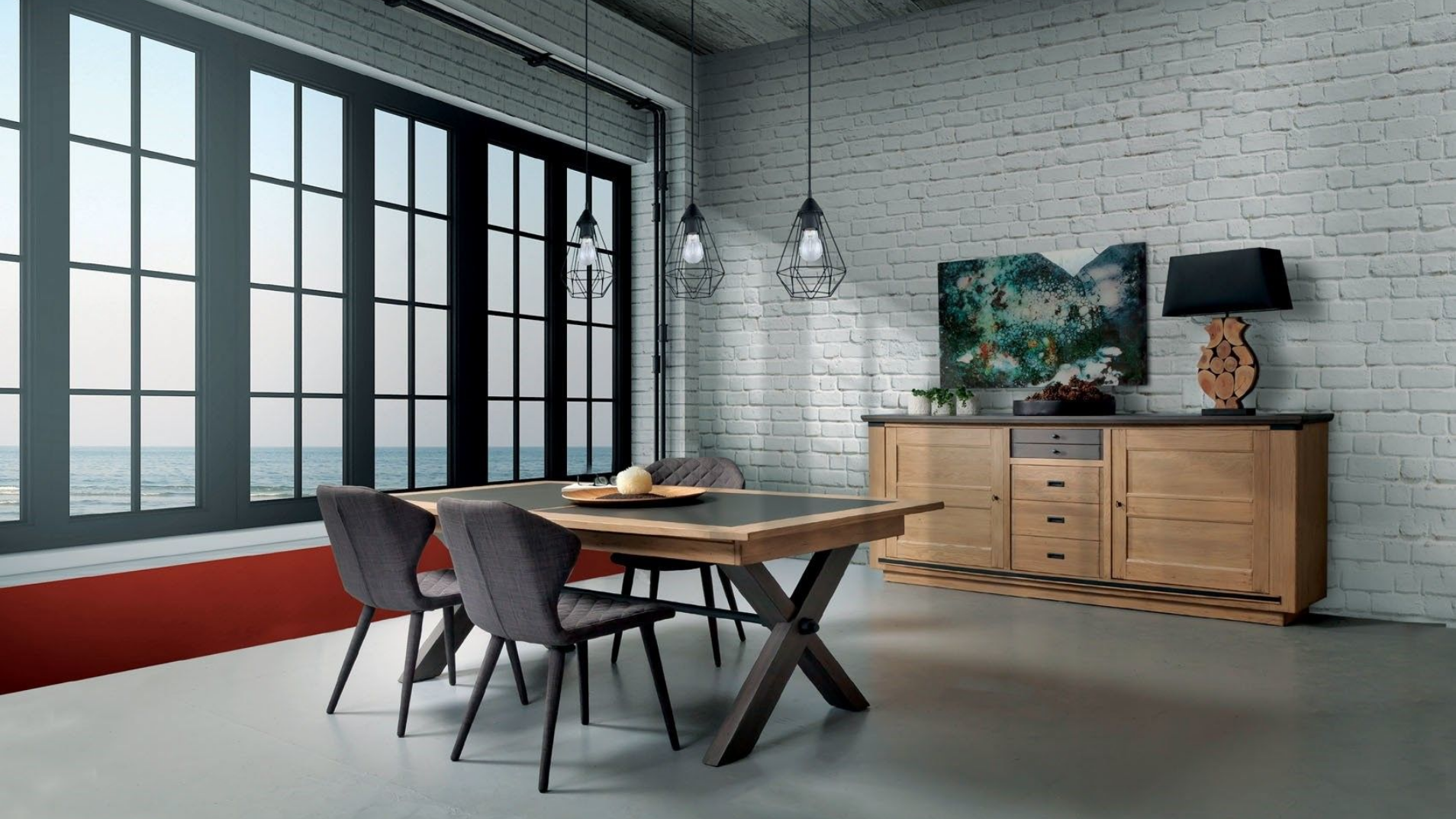 Salle à manger avec de grandes fenêtres, table, chaises, buffet et mur de briques.