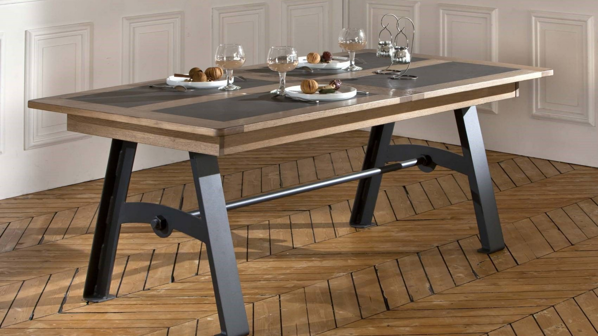 Table à manger avec pieds en métal noir, plateau en bois, dressée avec assiettes, verres et nourriture.