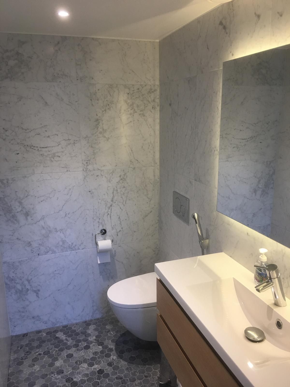 Vaalea kylpyhuone marmorilaatoituksella ja integroidulla LED-valaistuksella, Pintapiste Oy saneerauskohde.