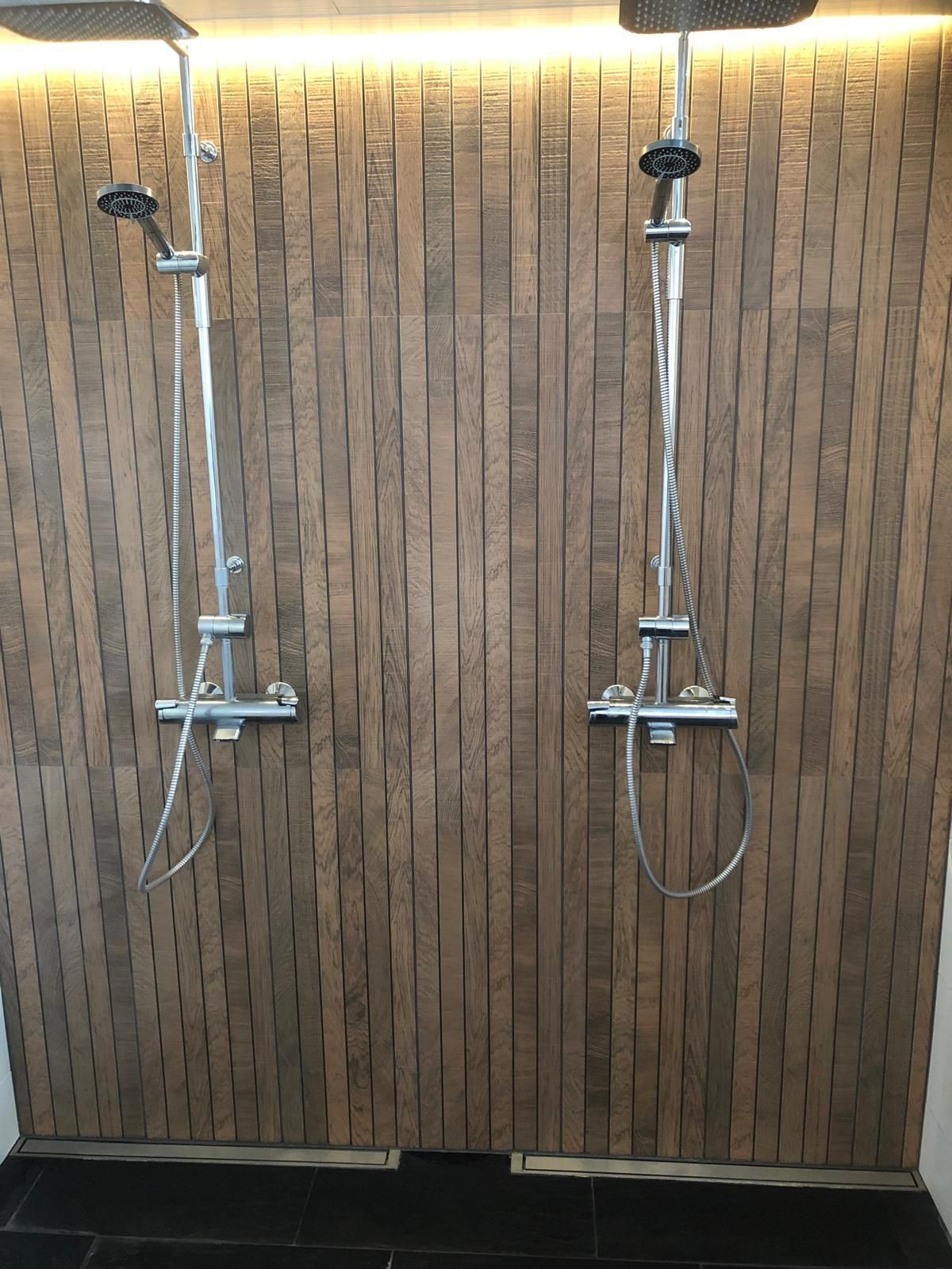 Kaksi sadesuihkua puukuvioisella tehosteseinällä, moderni kylpyhuoneremontti Turku Pintapiste Oy