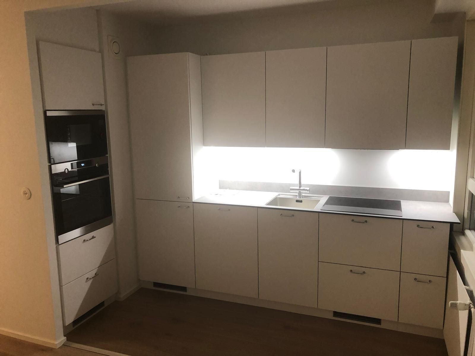 Moderni valkoinen keittiöpäivitys Turussa, minimalistiset kaapistot ja integroitu valaistus välitilassa.