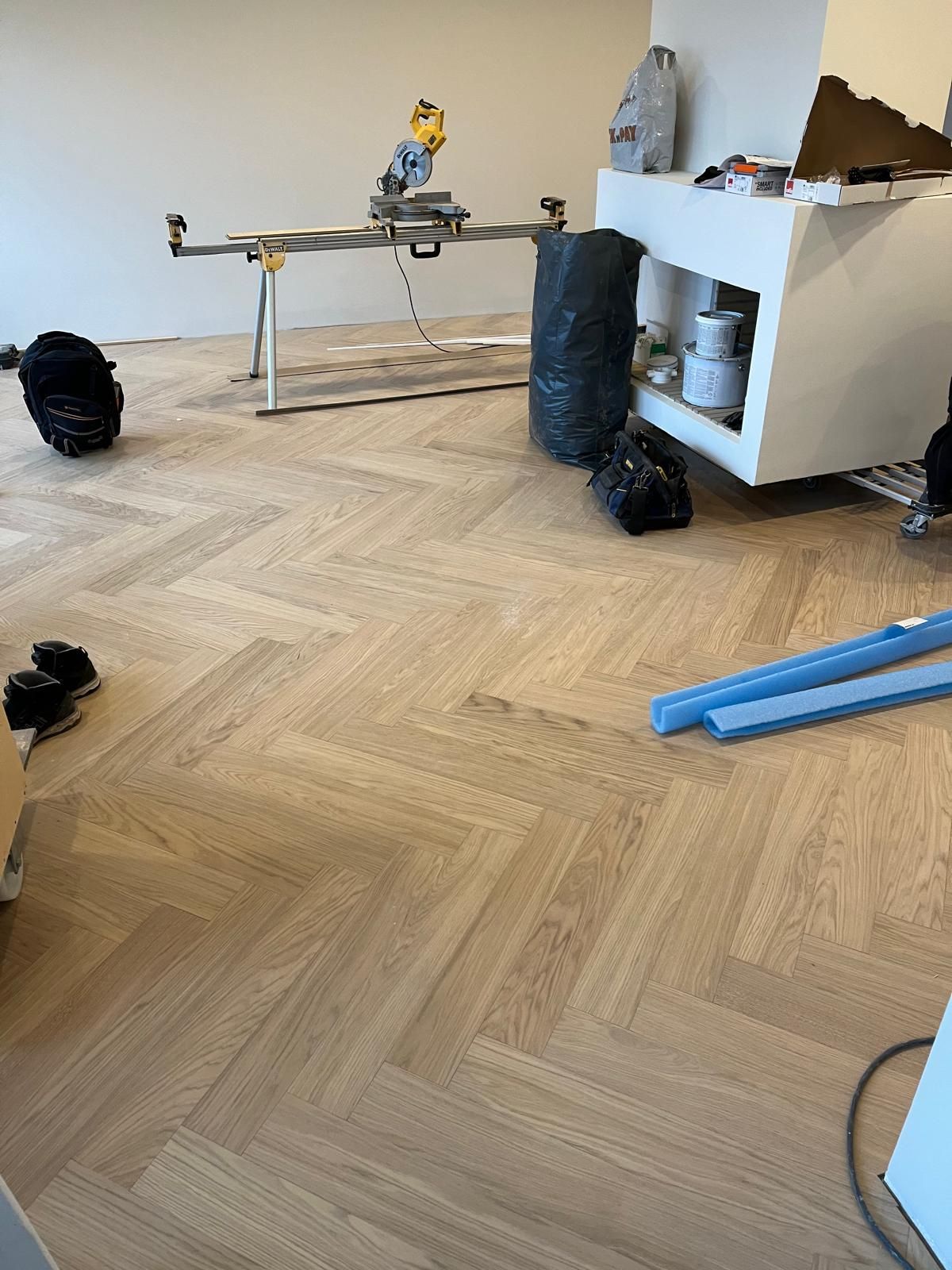 Kalanruotovinyylin asennus käynnissä Naantalissa, vaalea tammen sävyinen lattia ja Pintapiste Oy:n työkalut.