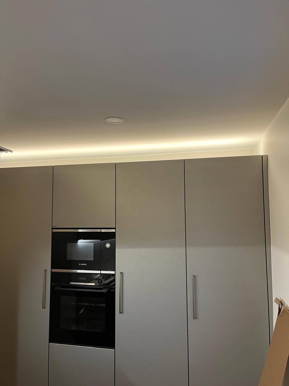 Moderni valkoinen keittiöpäivitys Turussa, minimalistiset kaapistot ja integroitu valaistus välitilassa.