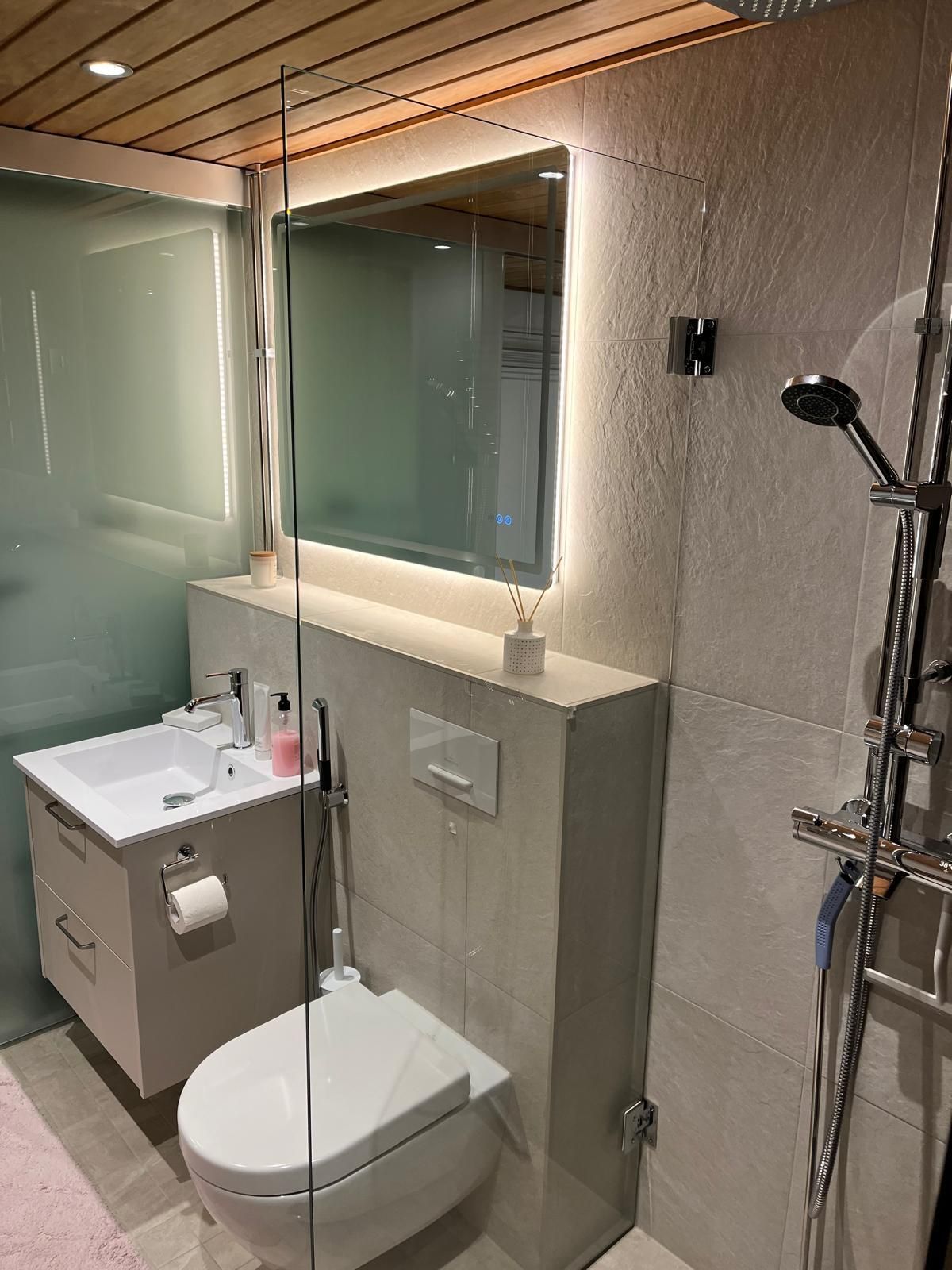 Moderni märkätilasaneeraus, jossa yhdistyvät vaaleat laatat, tyylikäs valaistus ja uusi sauna.