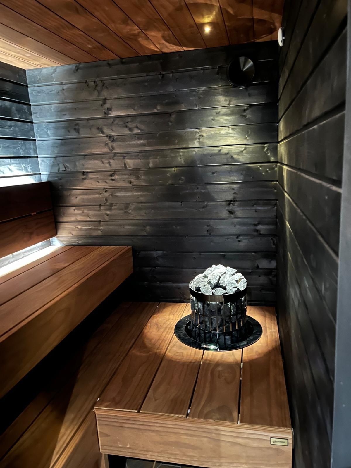 Moderni musta sauna pilarikiukaalla ja integroidulla LED-valaistuksella, Pintapiste Oy.