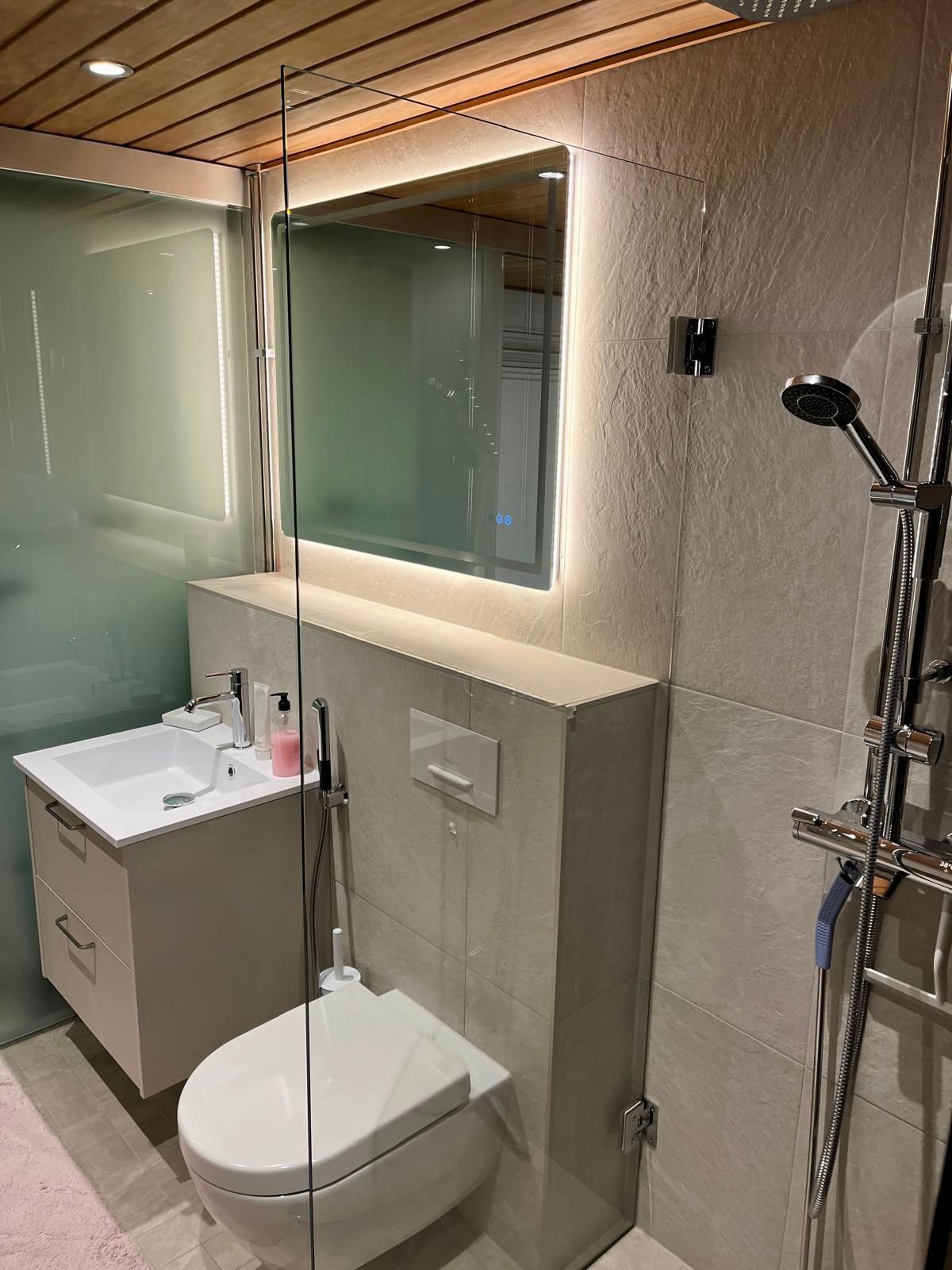 Moderni märkätilasaneeraus, jossa yhdistyvät vaaleat laatat, tyylikäs valaistus ja uusi sauna.