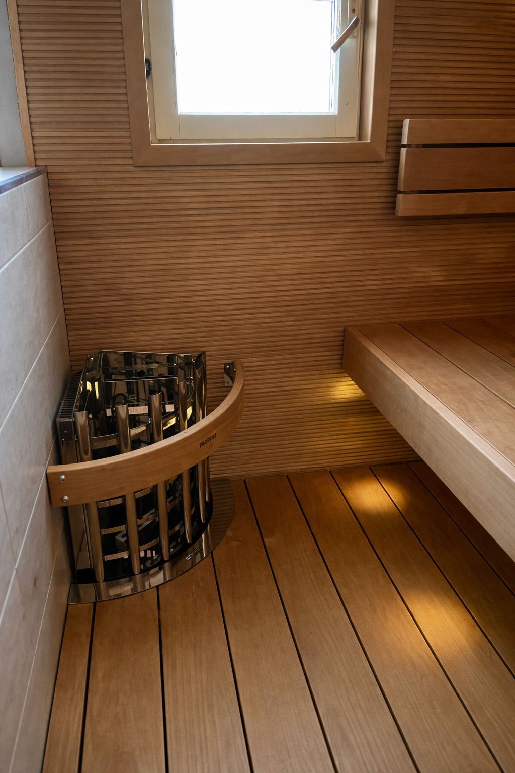 Kokonaisvaltainen märkätilasaneeraus, lasiseinä saunan ja kylpyhuoneen välillä.