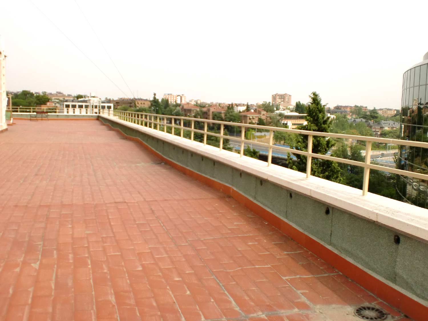 Una pasarela de ladrillo con barandilla y vista a una ciudad.