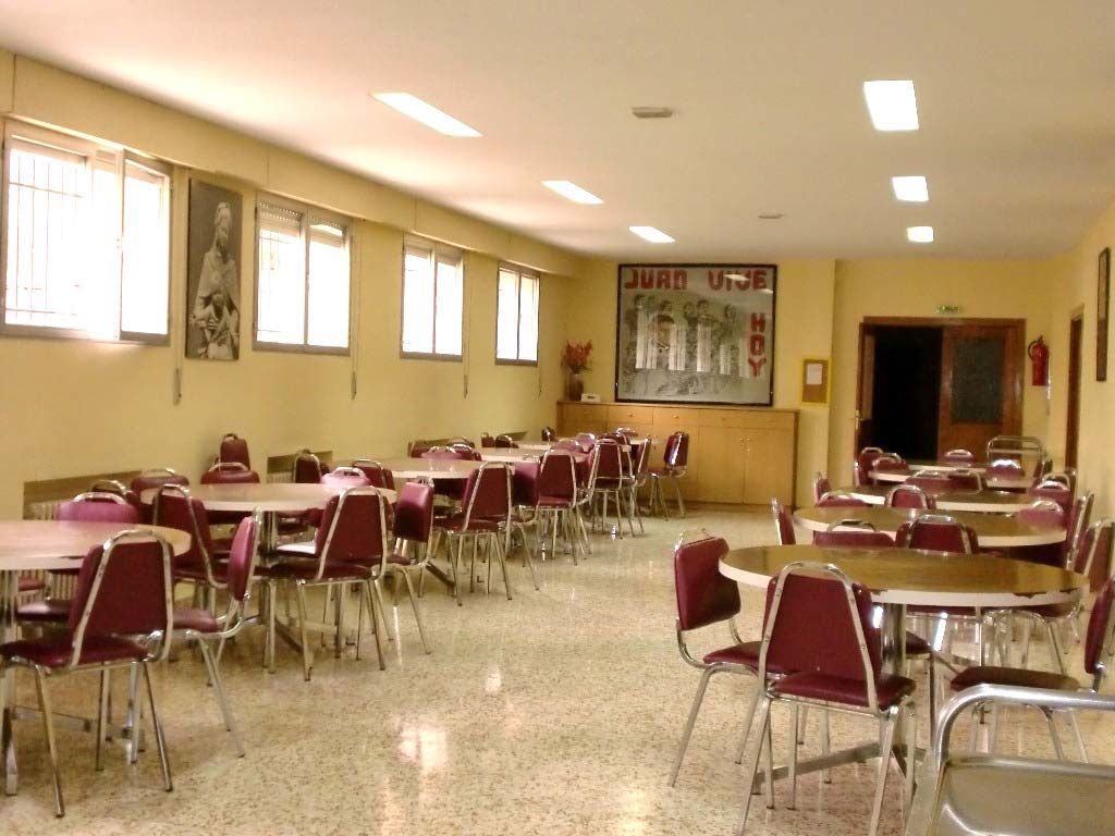 Un comedor con mesas y sillas y un cartel en la pared que dice
