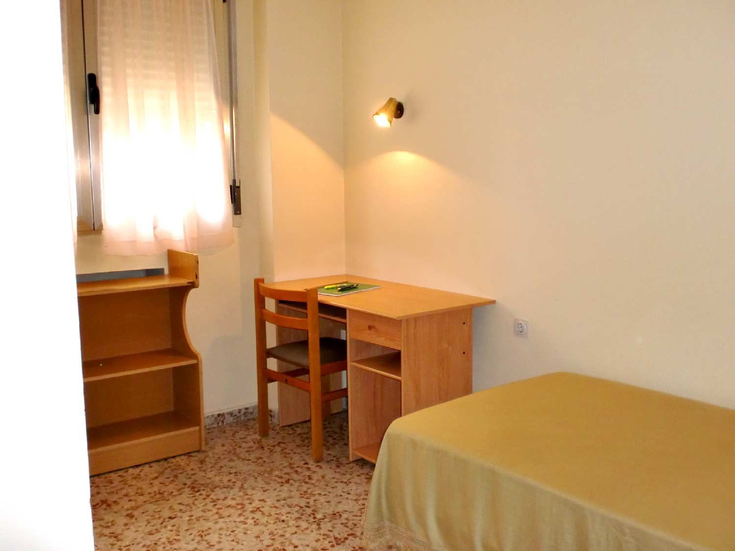 Un dormitorio con una cama individual, un escritorio y una silla.