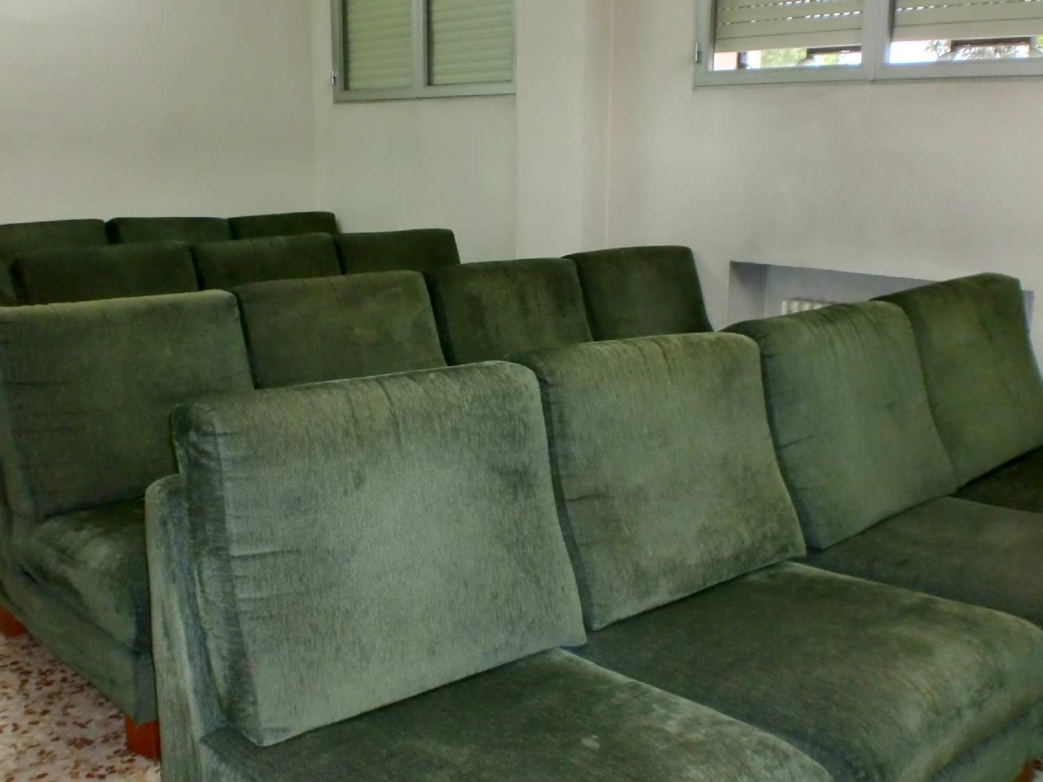Una fila de sofás verdes en una habitación con ventana.