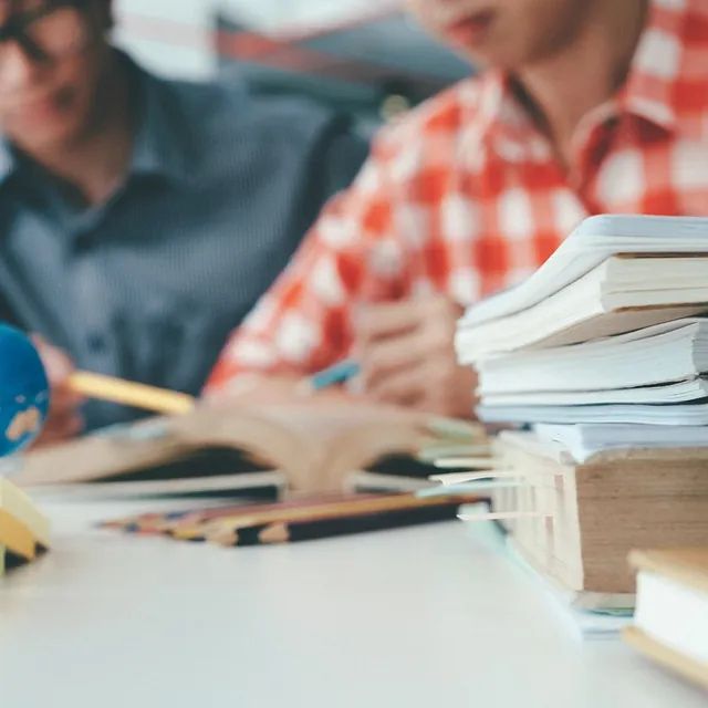 Un grupo de personas está sentado en una mesa con libros y lápices.
