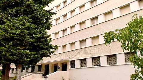 Un gran edificio con un árbol delante.
