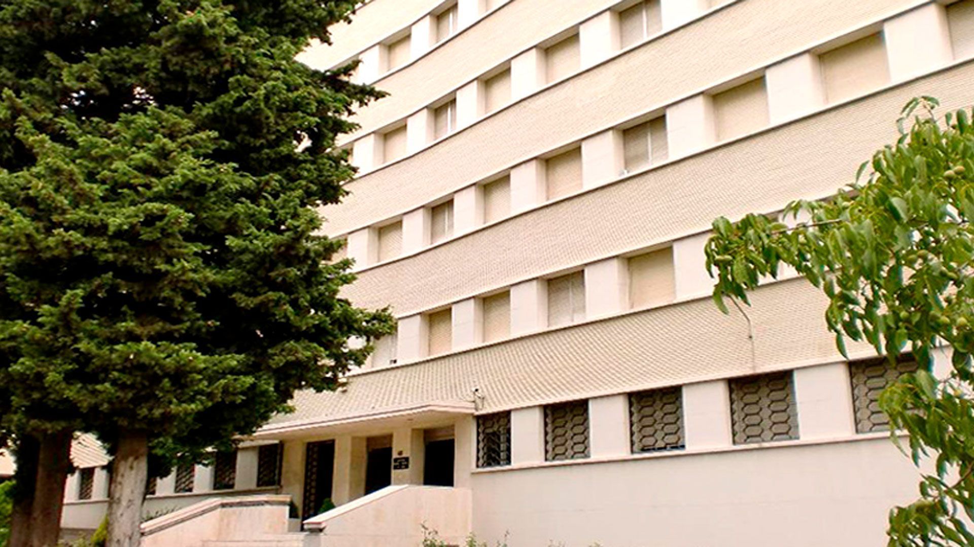Un gran edificio con un árbol delante.