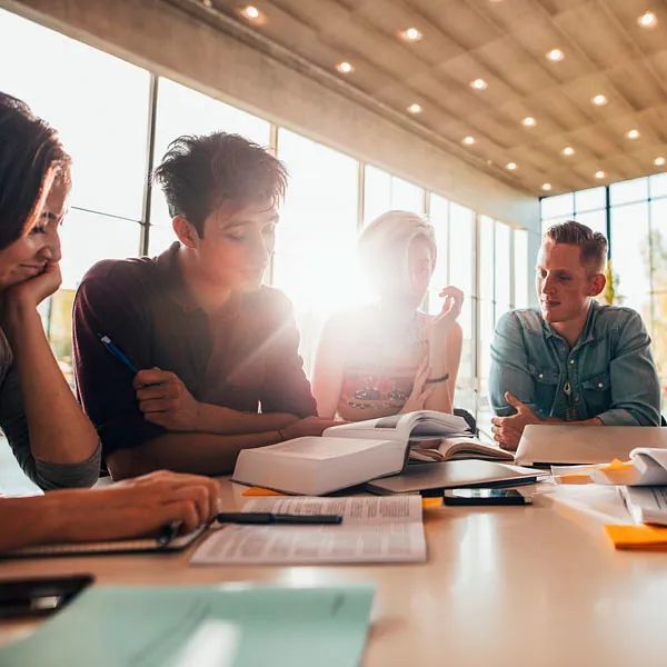 Un grupo de personas está sentada en una mesa leyendo libros.