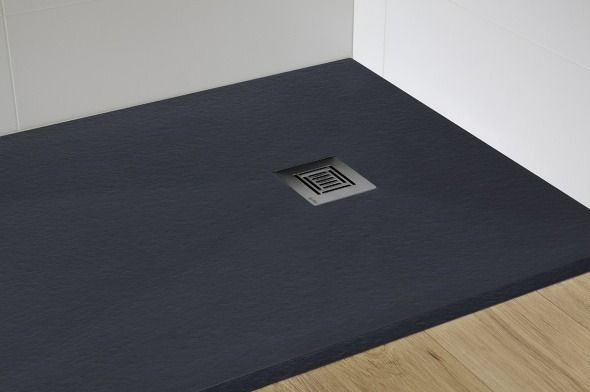 Un plato de ducha negro está colocado sobre un suelo de madera en un baño.