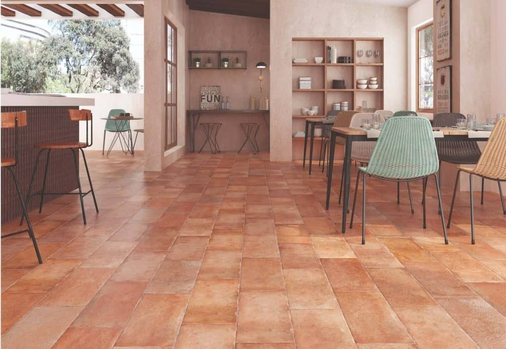 Un comedor con mesas y sillas y suelo de baldosas.