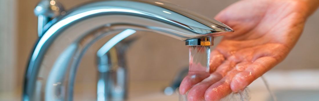 Una persona se lava las manos bajo el grifo de un baño.