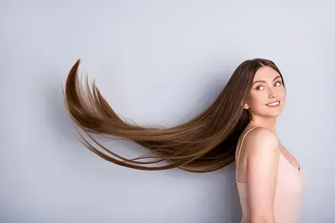 Una mujer con cabello muy largo está parada frente a una pared.