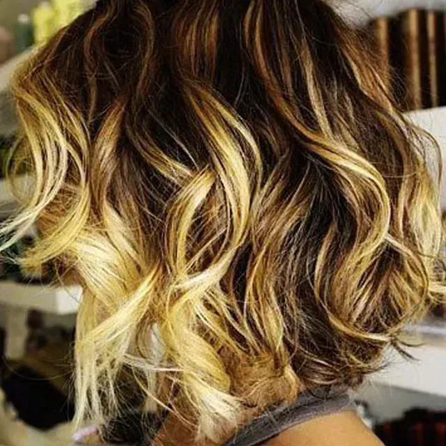Una mujer con cabello corto y ondulado lleva una camisa gris.