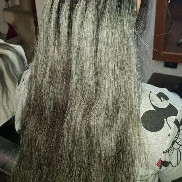 Una mujer con cabello largo y gris lleva una camiseta de Mickey Mouse.