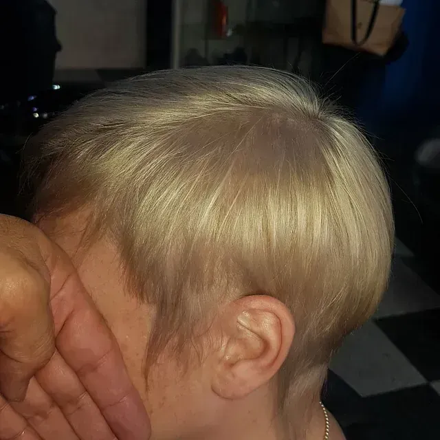 Una mujer con cabello rubio se cubre la cara con las manos.