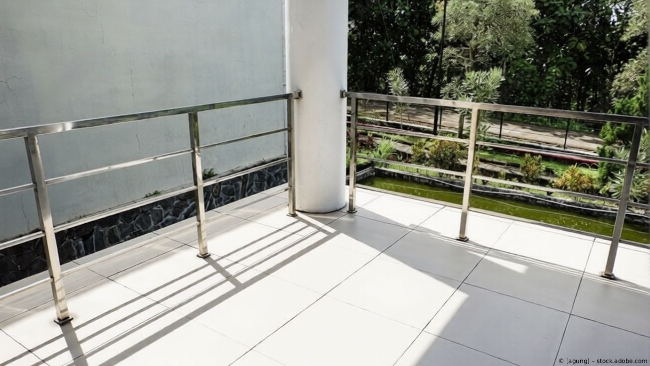 Sonniger Balkon mit Glas- und Metallgeländer mit Blick ins Grüne und aufs Wasser