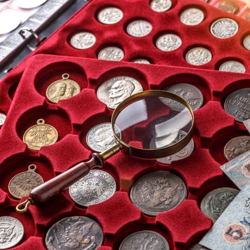 Una lupa se encuentra encima de una bandeja de monedas.