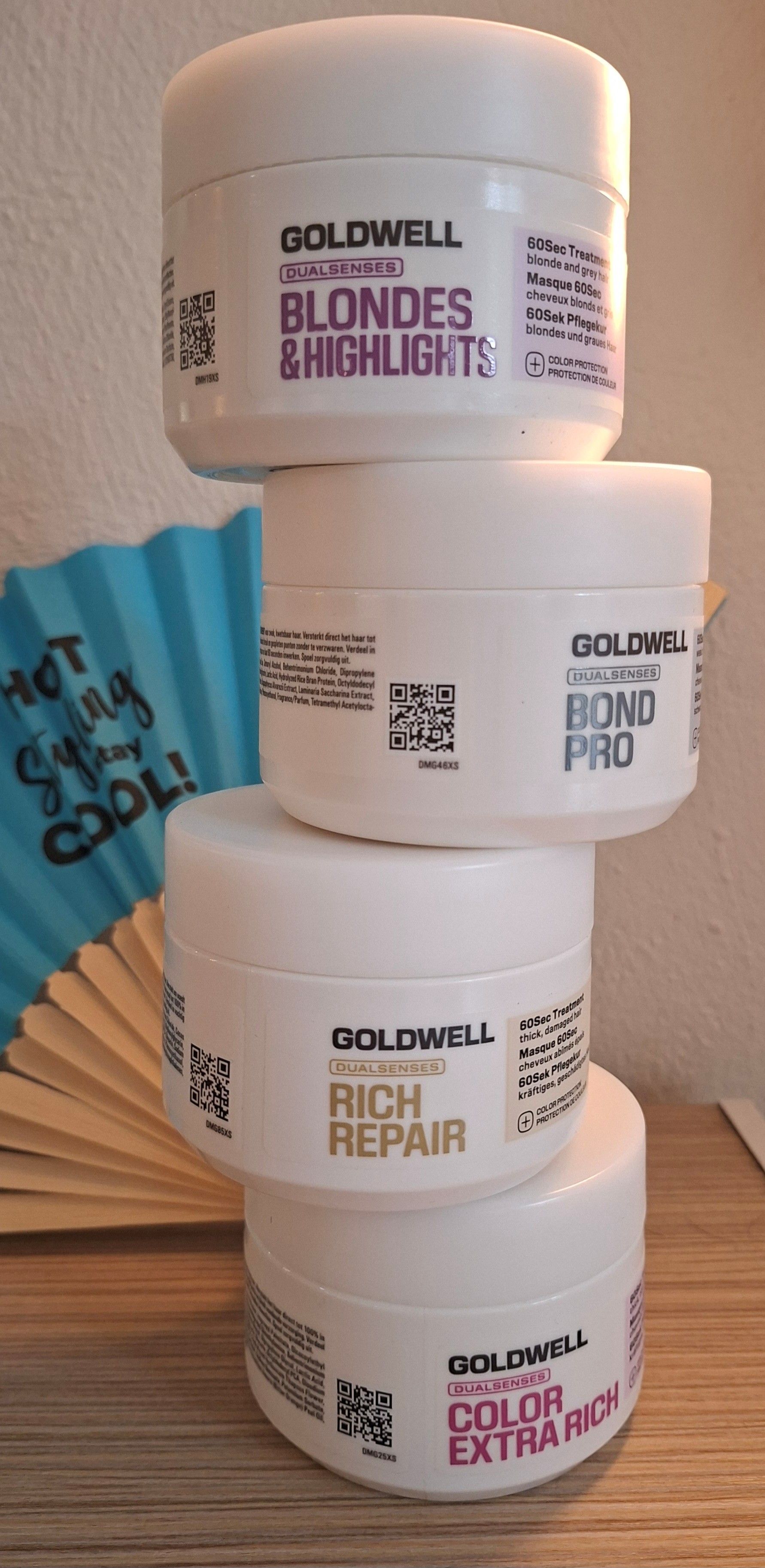 Gestapelte Goldwell-Haarkur-Tiegel mit einem blauen Sachet daneben