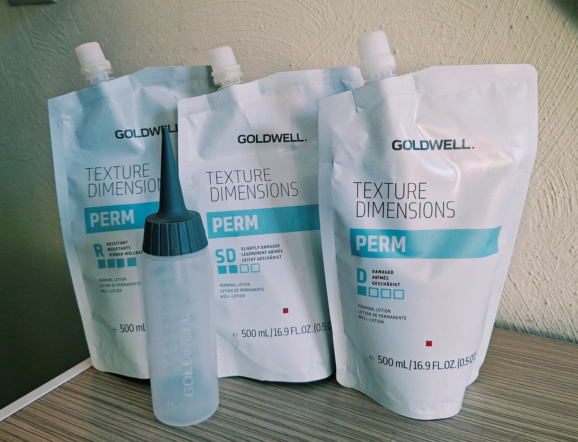 Dauerwellensachets und Applikationsflasche auf einem Tisch von Goldwell
