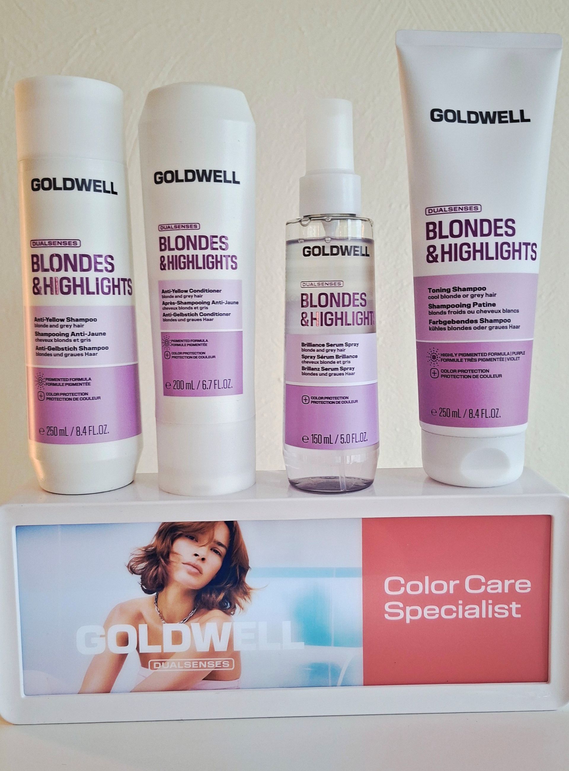 Goldwell Blonde-Highlights-Haarpflegeprodukte auf einem Regal, darunter eine Werbekarte