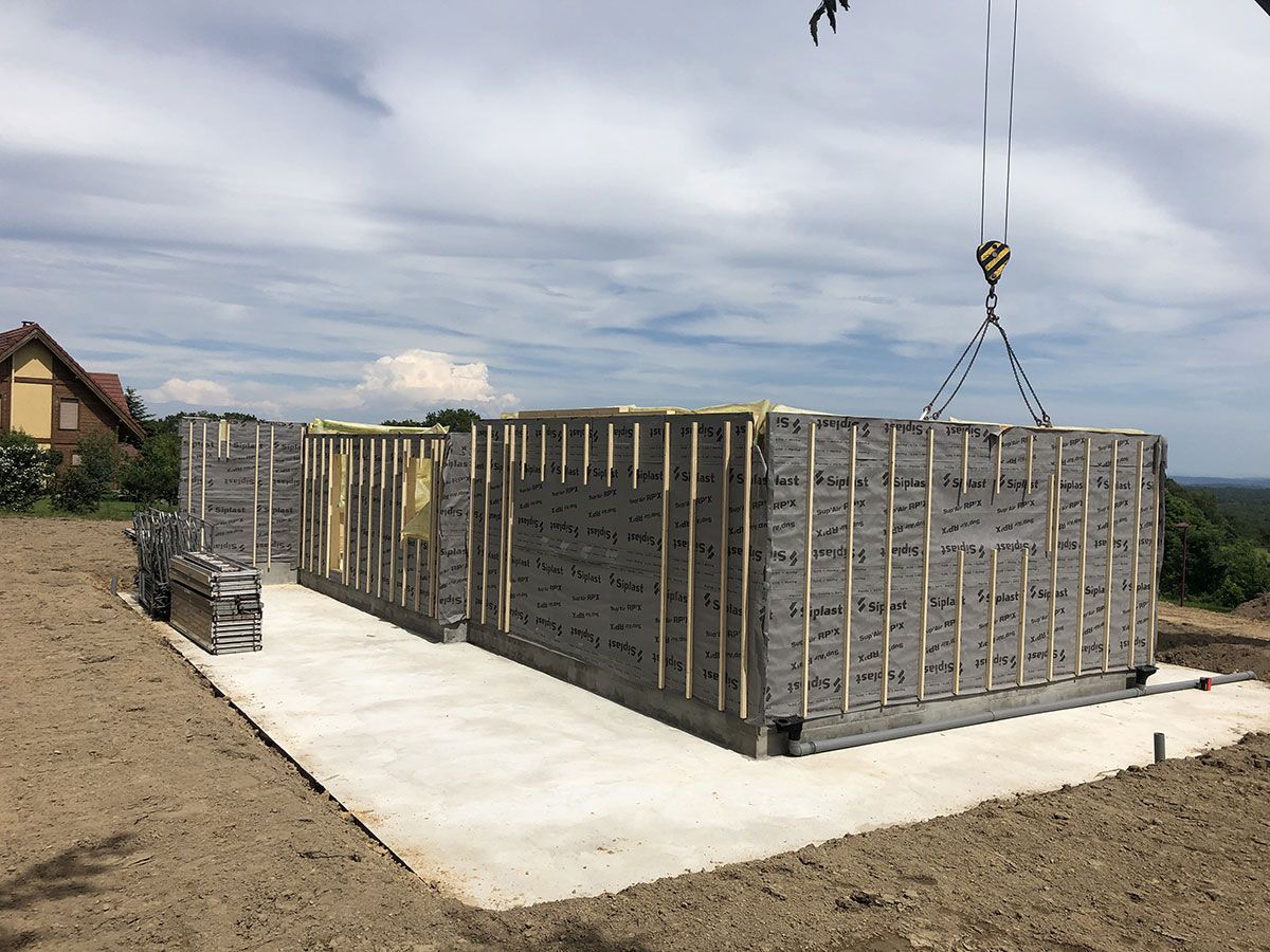 Base d'une maison à ossature en bois soutenue par une grue