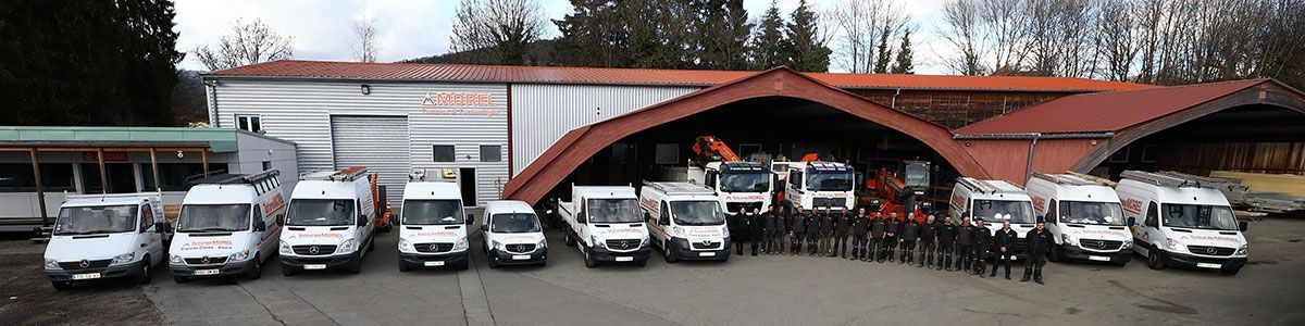 Equipe de l'entreprise Morel devant leur bâtiment et leurs véhicules