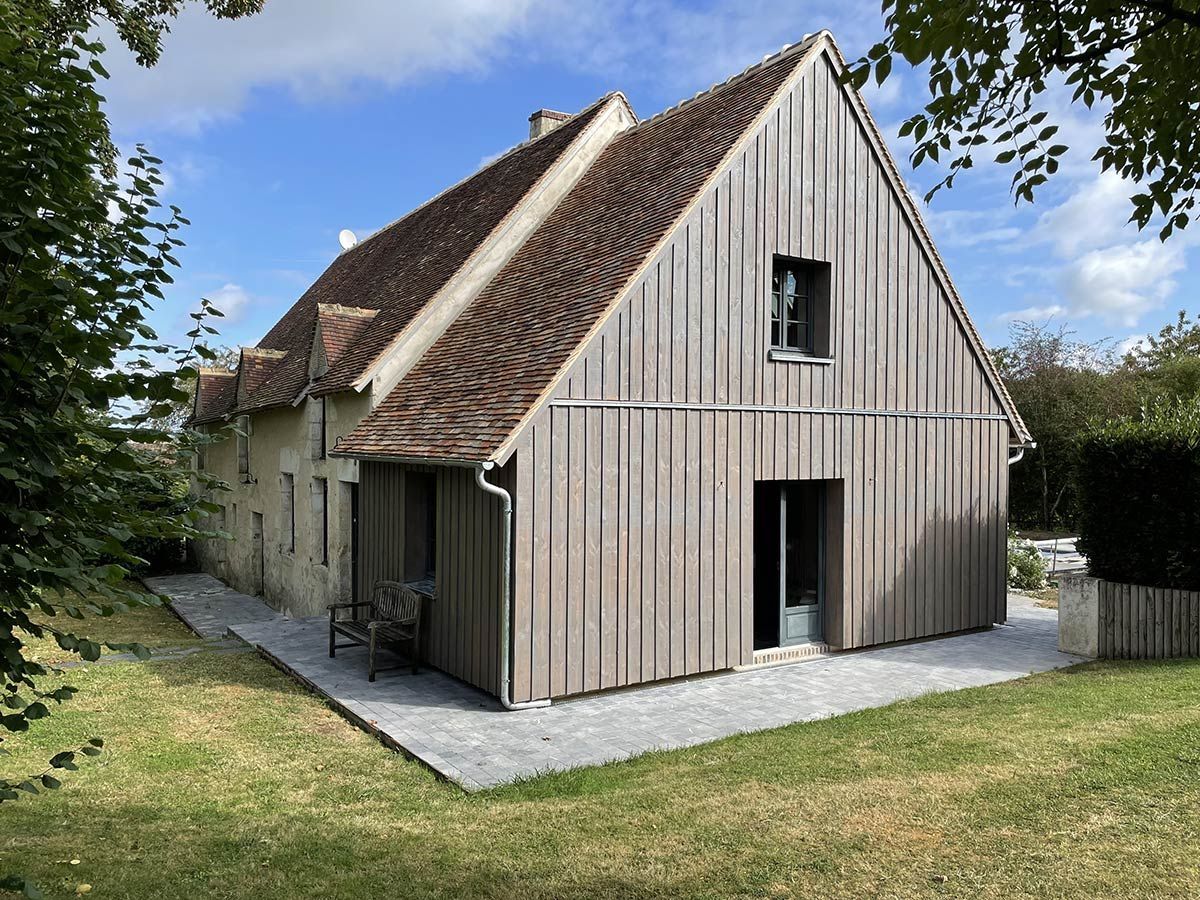 Extension d'une maison en pierre en bardage en bois