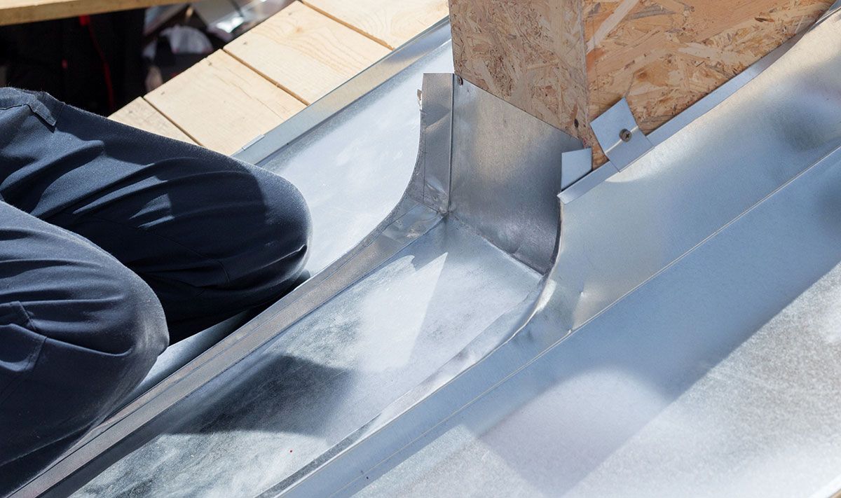 Homme qui installe des plaques en zinc sur un toit