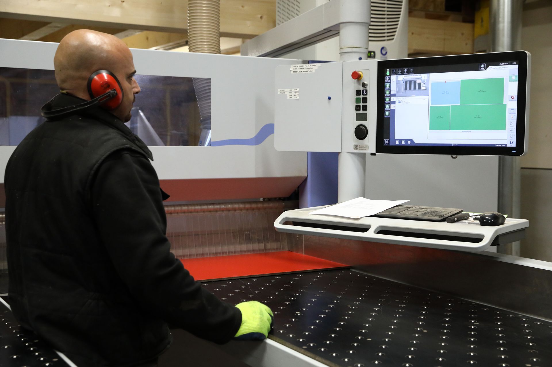 Un homme en train de regarder l'écran de contrôle d'une machine de découpe