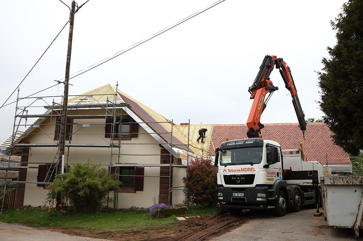Maison en cours de rénovation de couverture avec un camion-grue de l'entreprise Morel au premier plan