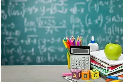 Útiles escolares (lápices, calculadora, libros, manzana, bloques) sobre un escritorio con un fondo de pizarra lleno de ecuaciones matemáticas.