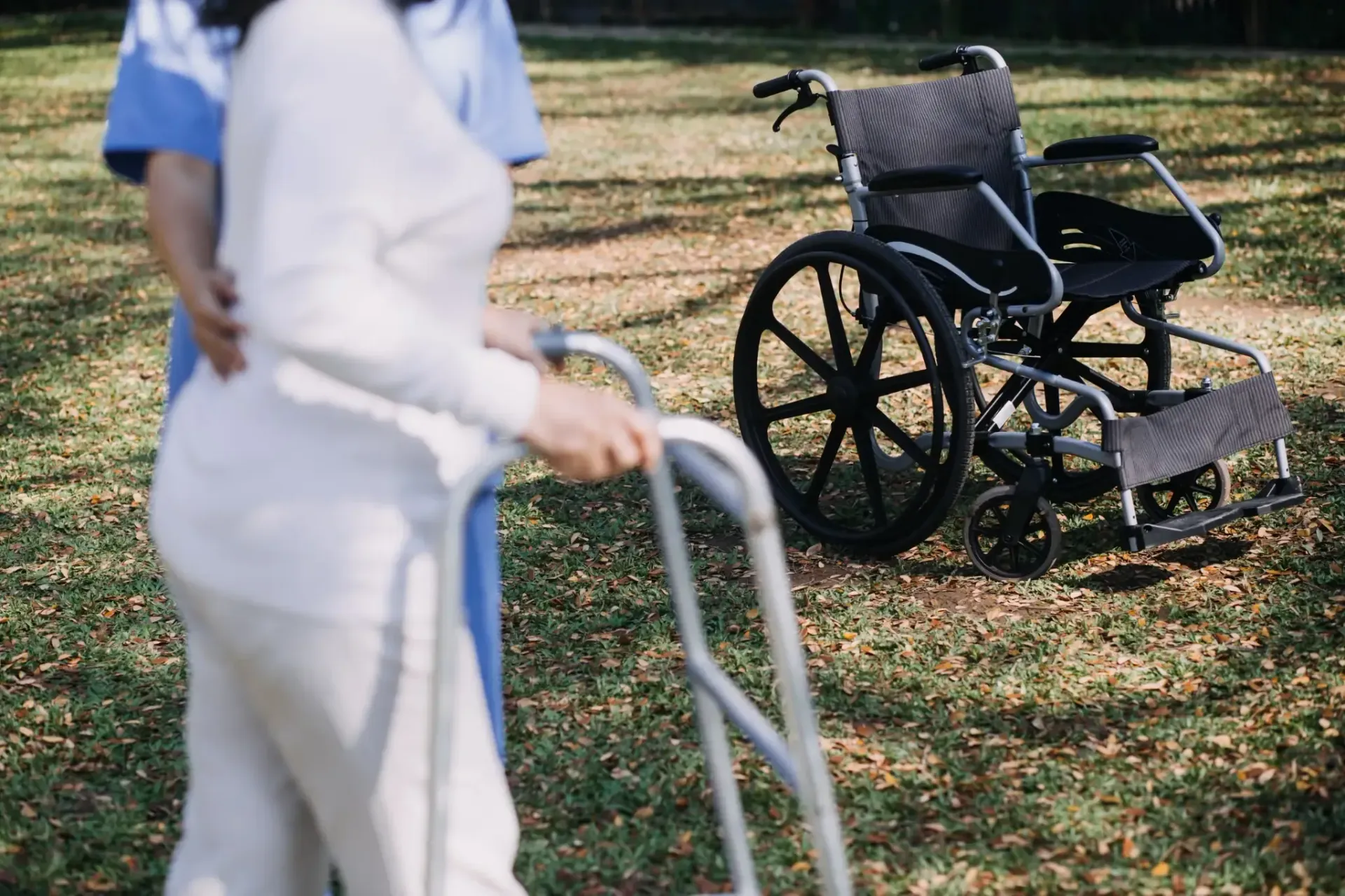 La mano de una persona en un bastón, la mano de otra persona en el hombro para apoyarse.