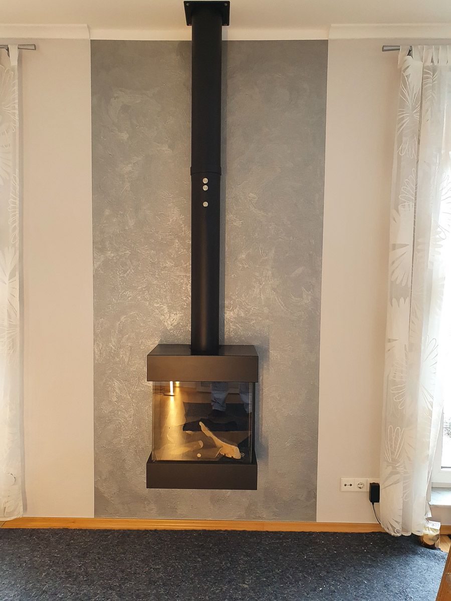 ein Kamin hängt an einer grauen Wand in einem Wohnzimmer - Referenzen der Malermeisterin Stefanie Würfel aus Bielefeld