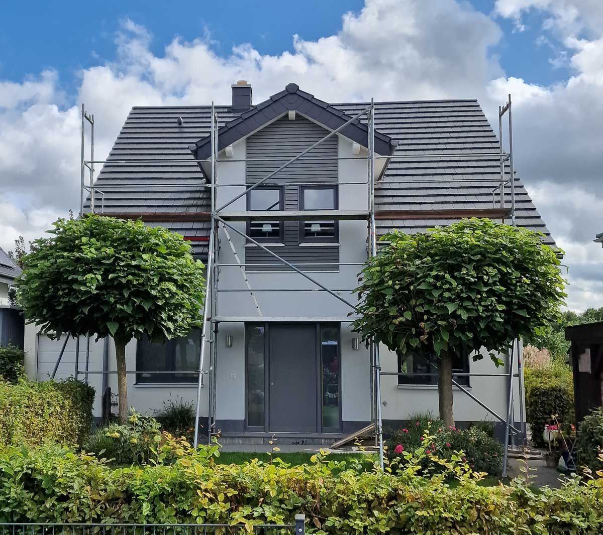 ein Haus mit einem Gerüst davor und zwei Bäumen - Referenzen der Malermeisterin Stefanie Würfel aus Bielefeld