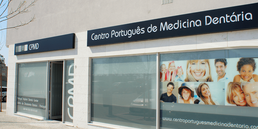 Exterior of the Centro Português de Medicina Dentária, featuring a sign, glass storefront, and posters of smiling people.