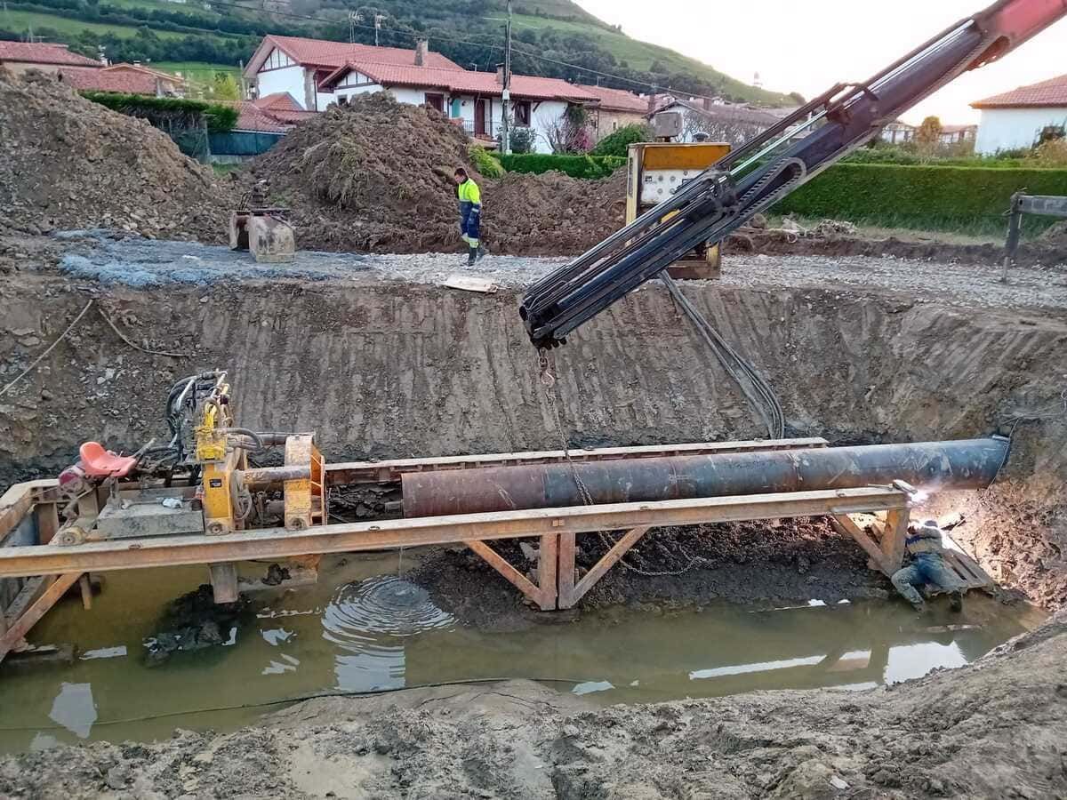 Una excavadora amarilla está moviendo rocas en un camino de tierra.