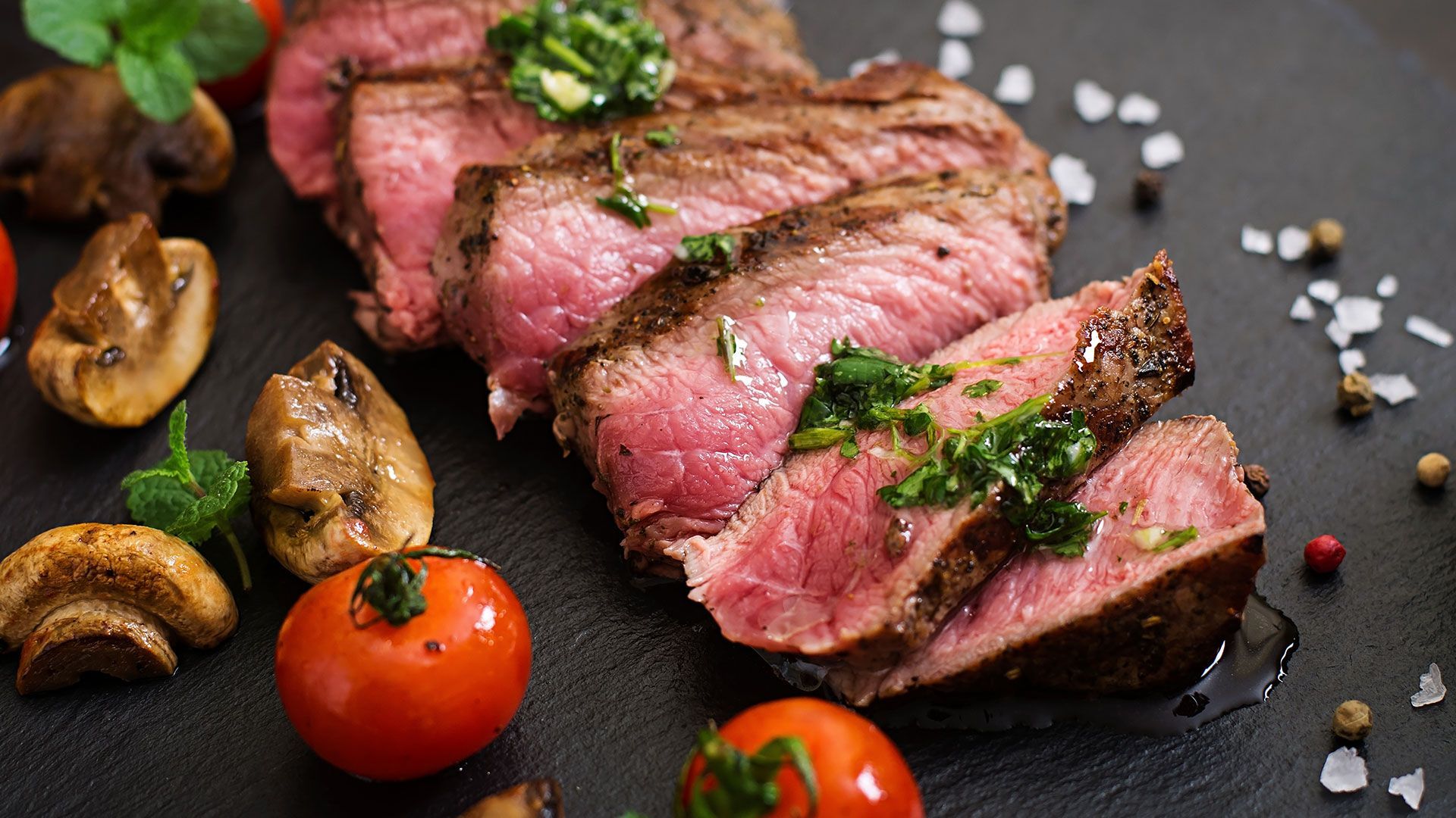 ein steak mit pilzen und tomaten auf einem tisch