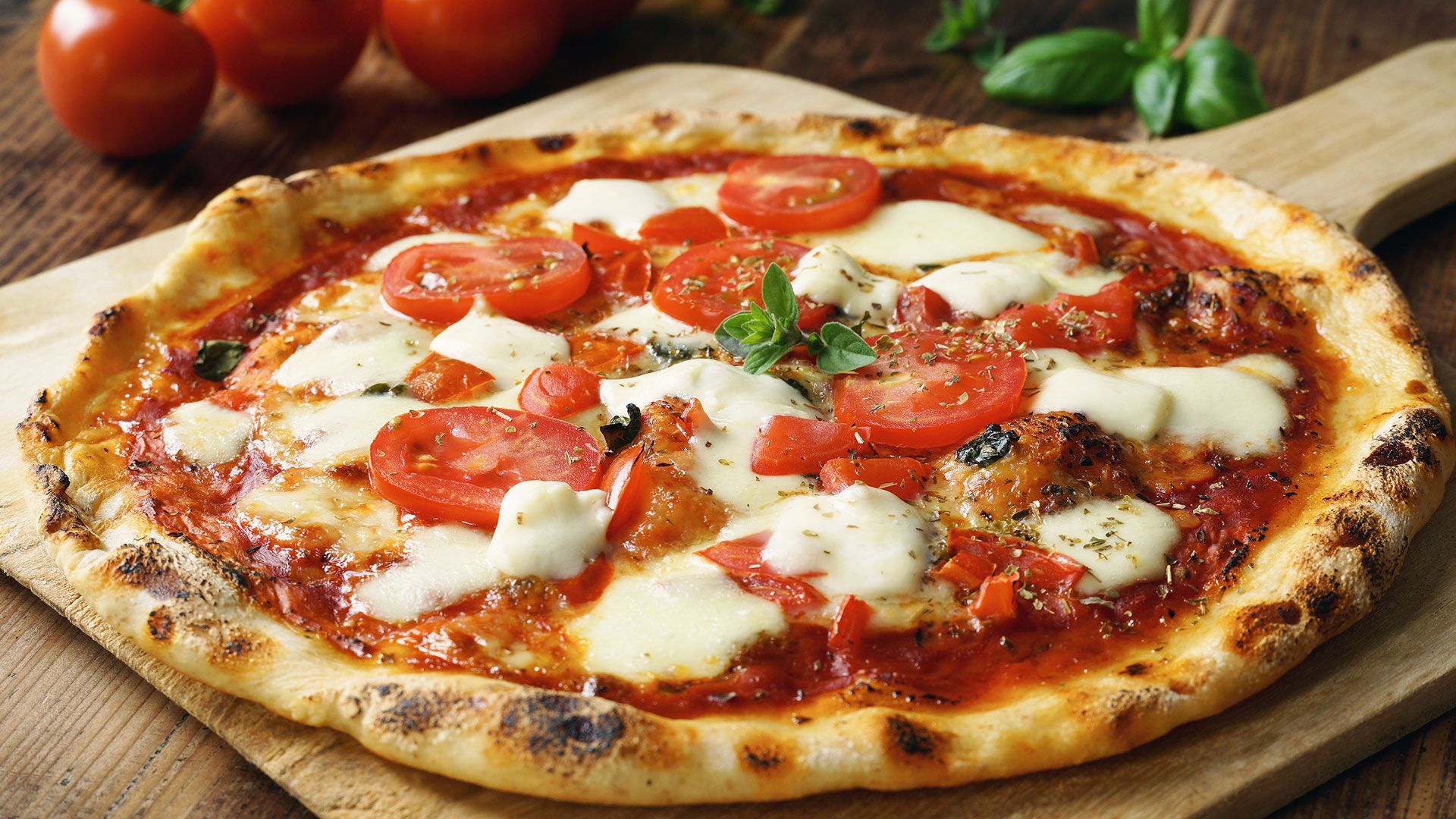 eine Pizza mit Tomaten und Käse auf einem Schneidebrett