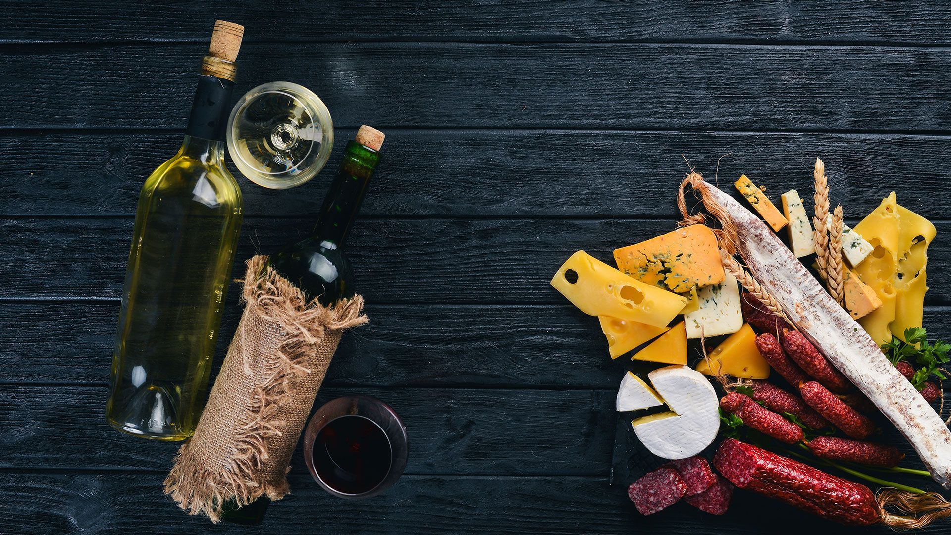 eine Flasche Wein und ein Glas Wein neben Käse und Wurst