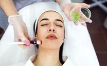 Tratamiento facial con cepillos y ventosas aplicado a una mujer recostada en un entorno de spa.