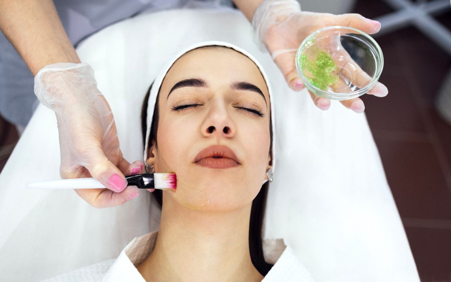 Tratamiento facial con cepillos y ventosas aplicado a una mujer recostada en un entorno de spa.