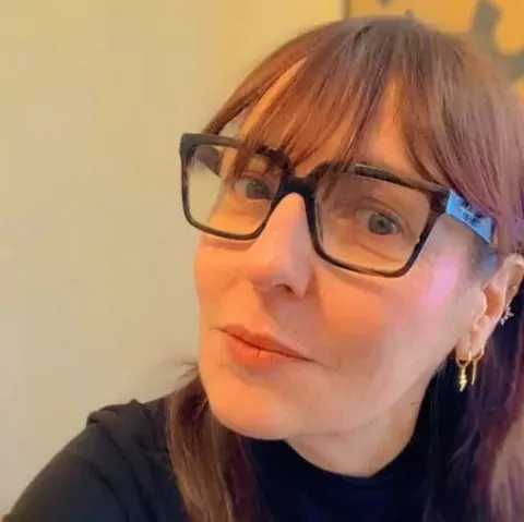 Un primer plano de una mujer que lleva gafas y pendientes.