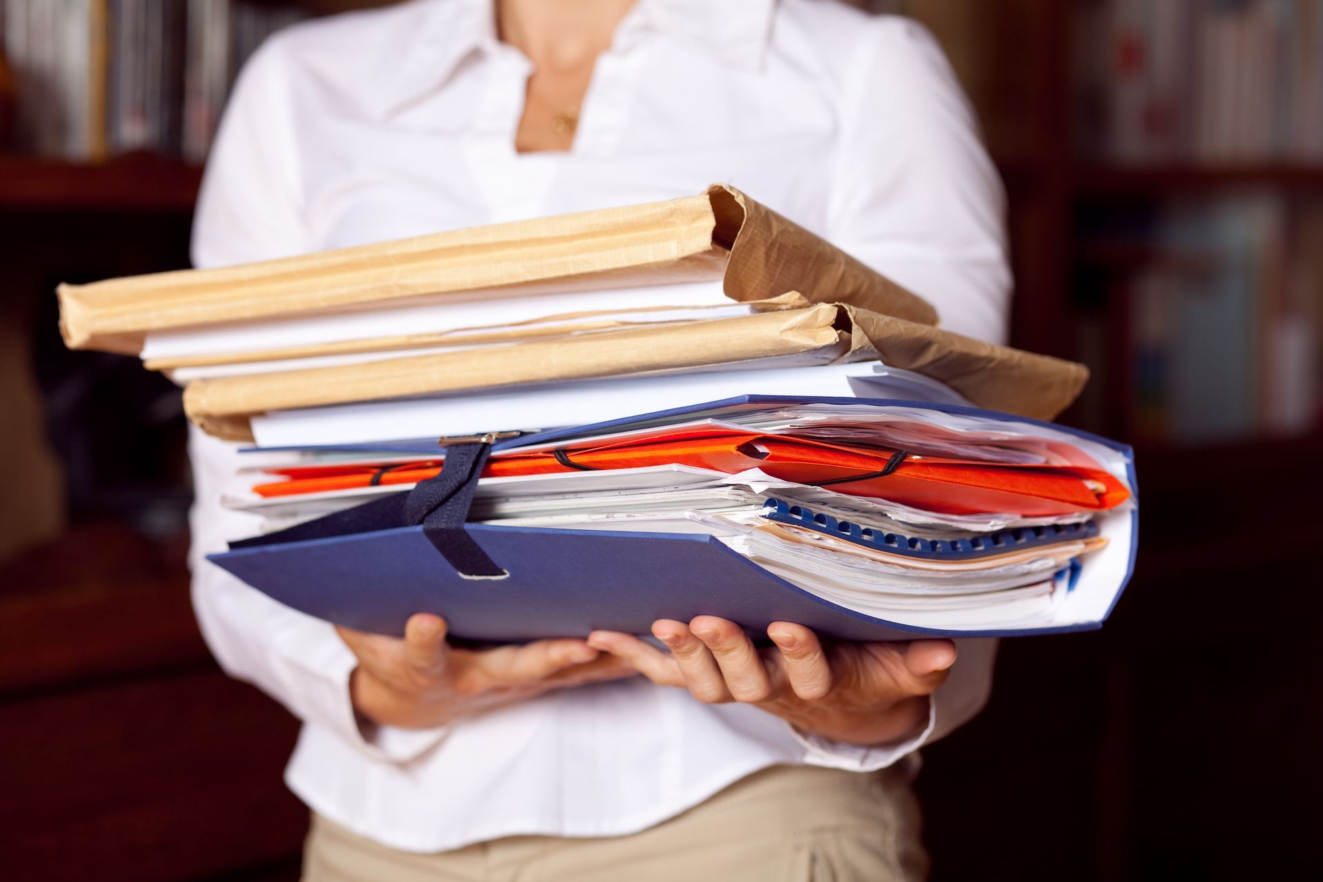 Personne tenant une pile de dossiers et de chemises blanches.
